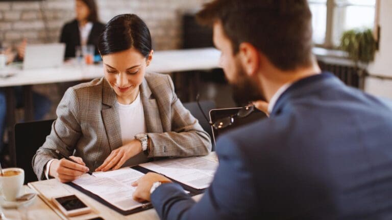 Mujer joven firmando su primer contrato laboral con asesoramiento profesional en derecho laboral