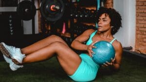 Mujer de más de 40 años entrenando con balón en un gimnasio luminoso, enfocada en su plan de pérdida de peso y hábitos saludables