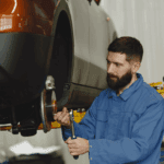Mecánico revisando un coche dentro de un concesionario con taller mecánico.