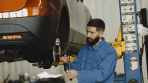 Mecánico revisando un coche dentro de un concesionario con taller mecánico.