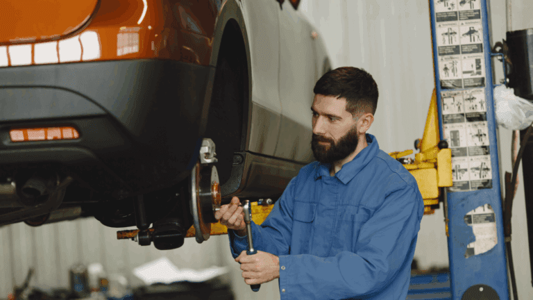 Mecánico revisando un coche dentro de un concesionario con taller mecánico.