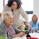 Mujer mayor acompañada por una profesional en una sesión de estimulación cognitiva para detectar señales tempranas de deterioro