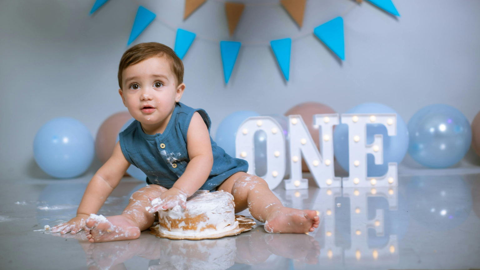 Bebé celebrando su primer cumpleaños con tarta durante sesión Smash Cake en Barcelona