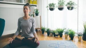 Mujer practicando yoga consciente en casa sobre esterilla con luz natural y ambiente de calma para bienestar físico y mental