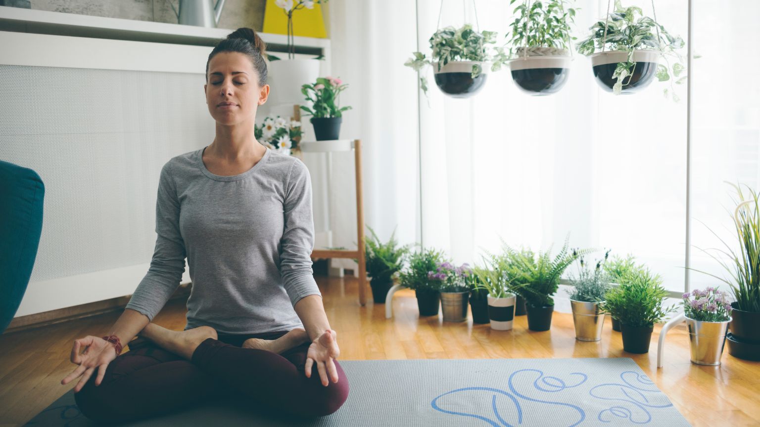 Mujer practicando yoga consciente en casa sobre esterilla con luz natural y ambiente de calma para bienestar físico y mental
