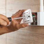 Instalaciones eléctricas seguras con electricista ajustando un enchufe de pared