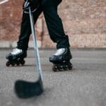 Jugador practicando hockey sobre patines con stick y patines en pista urbana