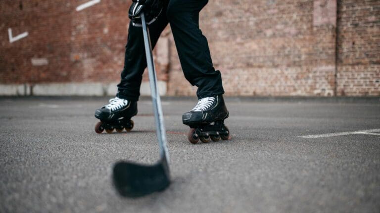 Jugador practicando hockey sobre patines con stick y patines en pista urbana