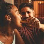 Pareja compartiendo churros con chocolate en Barcelona, disfrutando de un momento emocional y tradicional en un entorno acogedor.