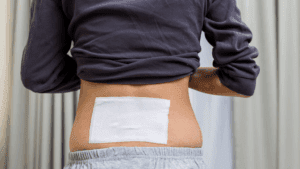 Persona usando parches musculares naturales para relajar los hombros después de entrenar.