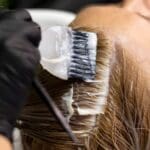 Peluquera profesional en salón de belleza en Madrid aplicando tratamiento natural a clienta con cabello sano y brillante