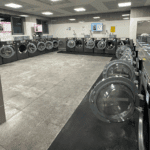 Lavadoras industriales en funcionamiento dentro de un espacio que ofrece servicios de lavandería rápidos y cómodos.