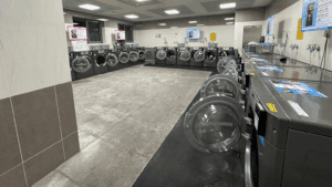 Lavadoras industriales en funcionamiento dentro de un espacio que ofrece servicios de lavandería rápidos y cómodos.