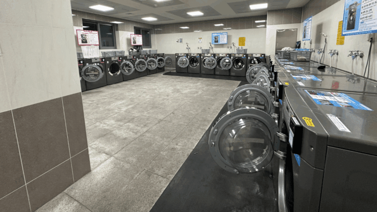 Lavadoras industriales en funcionamiento dentro de un espacio que ofrece servicios de lavandería rápidos y cómodos.