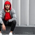 Joven con ropa urbana cómoda combinando sudadera oversize y joggers en entorno urbano