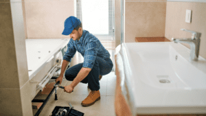 Técnico ajustando fontanería en baño durante reforma