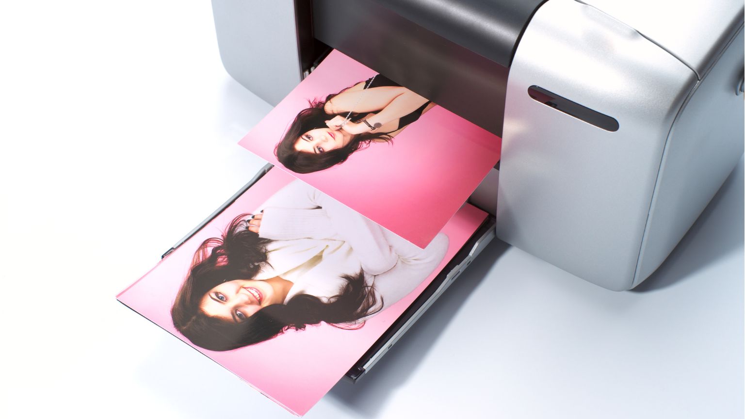 Persona imprimiendo fotos desde el móvil en casa, con copias en papel sobre la mesa.