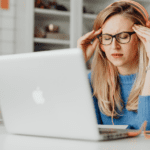 Mujer con dolor de cabeza trabajando frente a un ordenador portátil