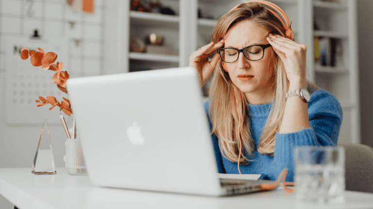 Mujer con dolor de cabeza trabajando frente a un ordenador portátil