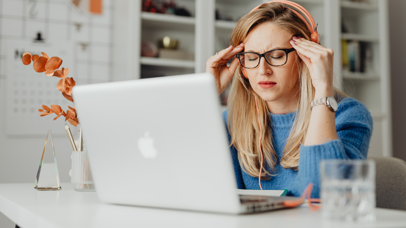 Mujer con dolor de cabeza trabajando frente a un ordenador portátil