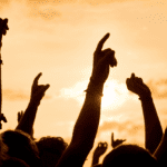 Público con las manos en alto disfrutando de un evento en vivo.