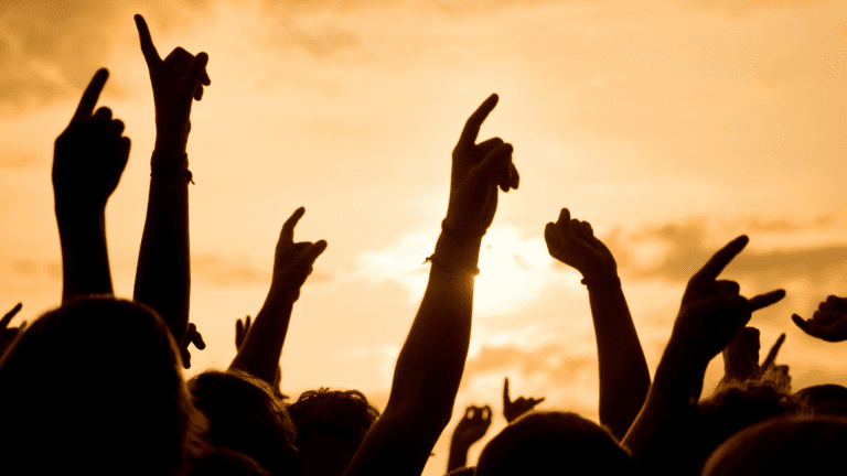 Público con las manos en alto disfrutando de un evento en vivo.