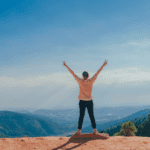 Persona con los brazos en alto disfrutando de la vista en la montaña.