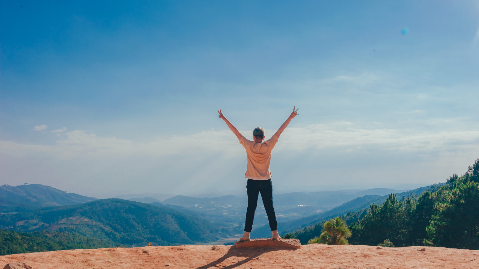 Persona con los brazos en alto disfrutando de la vista en la montaña.