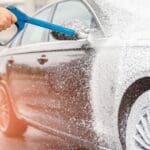Lavado de coches profesional aplicando espuma a un vehículo para su limpieza profunda