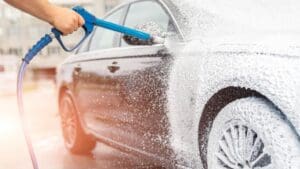 Lavado de coches profesional aplicando espuma a un vehículo para su limpieza profunda