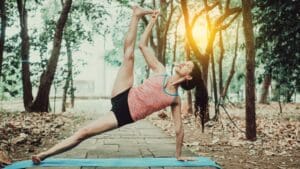 Persona haciendo yoga para principiantes en esterilla sobre césped en entorno natural, ideal para entrenamientos suaves