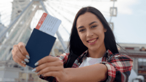 Mujer joven sonriente mostrando su pasaporte y billete de avión, lista para viajar al extranjero, simbolizando movilidad internacional y procesos migratorios.