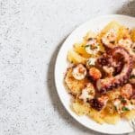 Pulpo a la mugardesa servido en cazuela de barro con patatas, pimientos y salsa tradicional gallega.