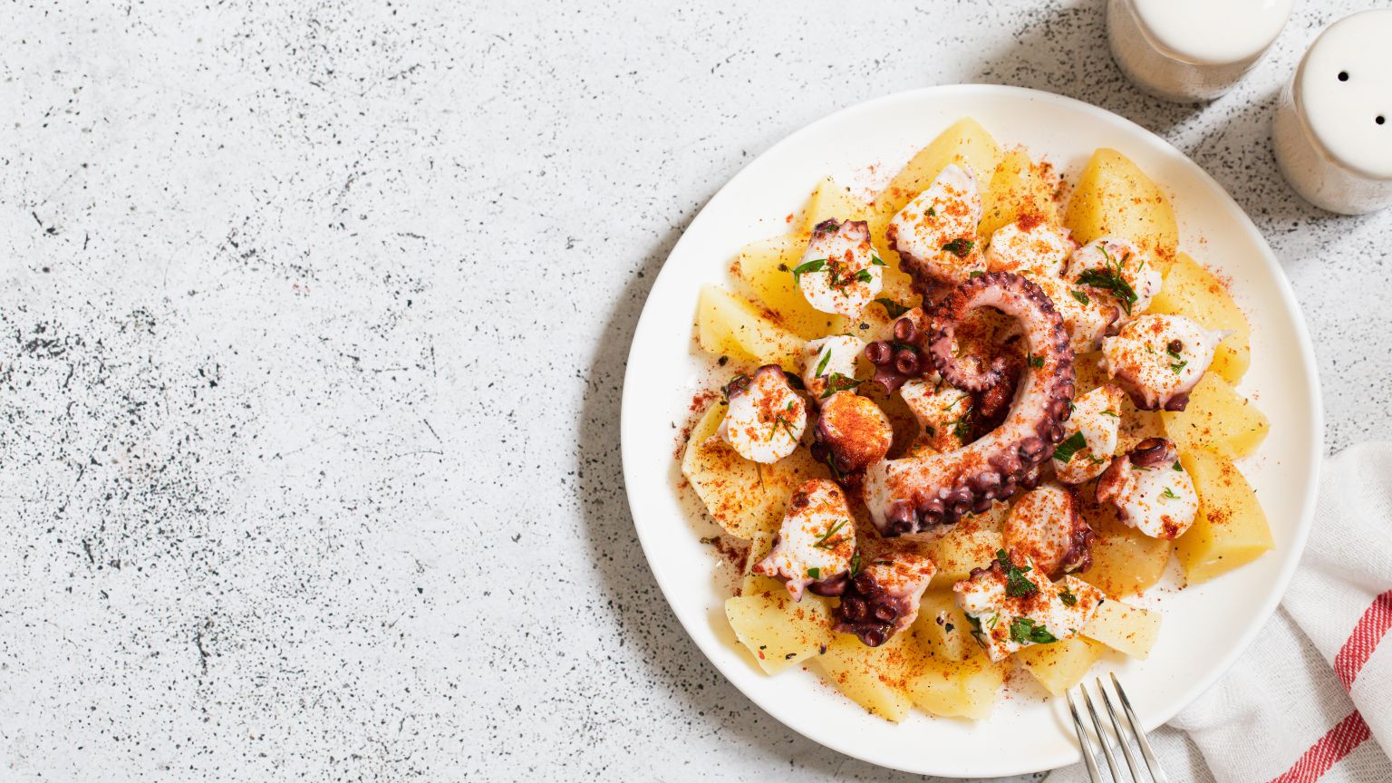 Pulpo a la mugardesa servido en cazuela de barro con patatas, pimientos y salsa tradicional gallega.