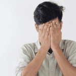 Hombre con gesto de angustia cubriéndose el rostro con las manos, representando estrés emocional o crisis de salud mental.