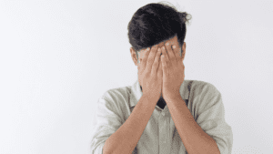 Hombre con gesto de angustia cubriéndose el rostro con las manos, representando estrés emocional o crisis de salud mental.