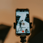 Grabación con móvil en estudio de vídeo donde se enfoca a una persona preparando una caja frente a focos de iluminación profesional.