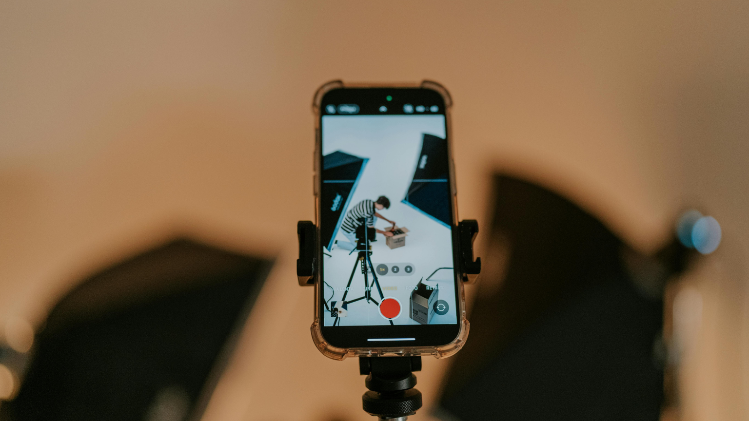 Grabación con móvil en estudio de vídeo donde se enfoca a una persona preparando una caja frente a focos de iluminación profesional.