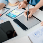 Diseño de interfaz de usuario en equipo creativo con tabletas gráficas y wireframes sobre escritorio.