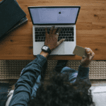 Persona realizando compra online desde portátil con tarjeta de crédito en mano.