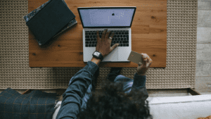 Persona realizando compra online desde portátil con tarjeta de crédito en mano.