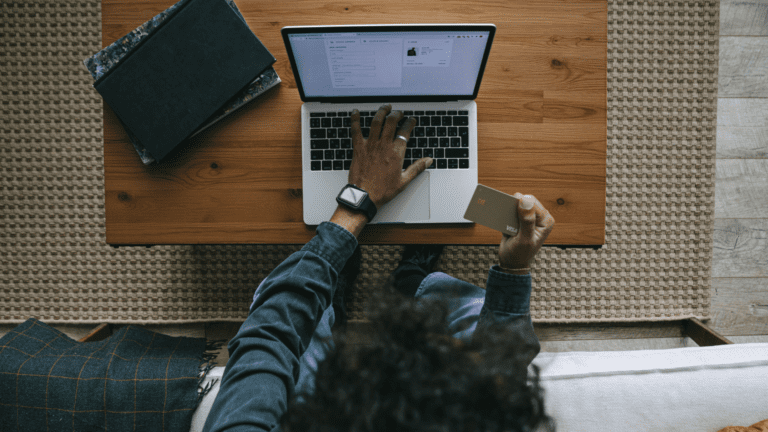 Persona realizando compra online desde portátil con tarjeta de crédito en mano.