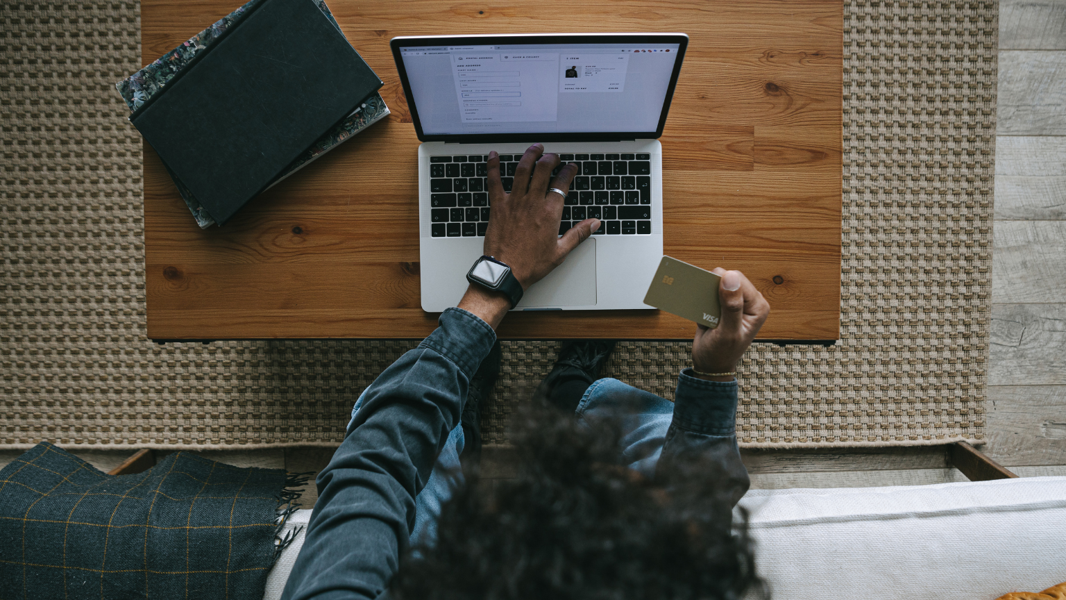 Persona realizando compra online desde portátil con tarjeta de crédito en mano.