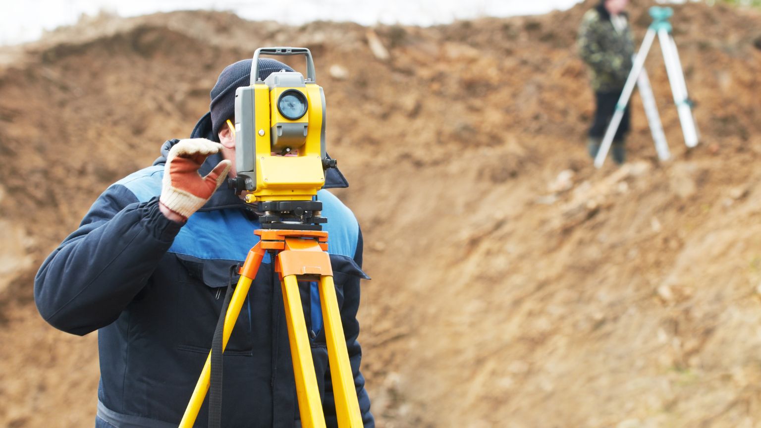 Topógrafo realizando un levantamiento de terreno con estación total.