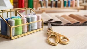 Materiales básicos para empezar en la costura: agujas, hilos, tijeras y tela organizados en una mesa de trabajo para principiantes.