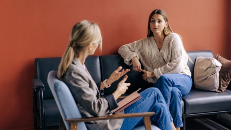 Mujer joven en sesión de terapia psicológica iniciando su proceso de sanación tras un trauma sexual, acompañada por una profesional en un entorno seguro