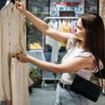 Mujer evaluando prenda de ropa sostenible en tienda de moda ética