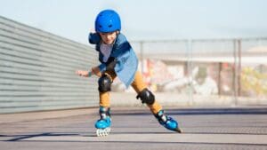 Niño practicando patinaje con protecciones en una escuela de patinaje infantil, desarrollando equilibrio y coordinación al aire libre.