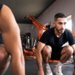 Entrenador personal ayudando a evitar lesiones durante un ejercicio sencillo.