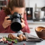 Fotógrafa de gastronomía capturando platos gourmet en un restaurante con luz natural para marketing visual profesional